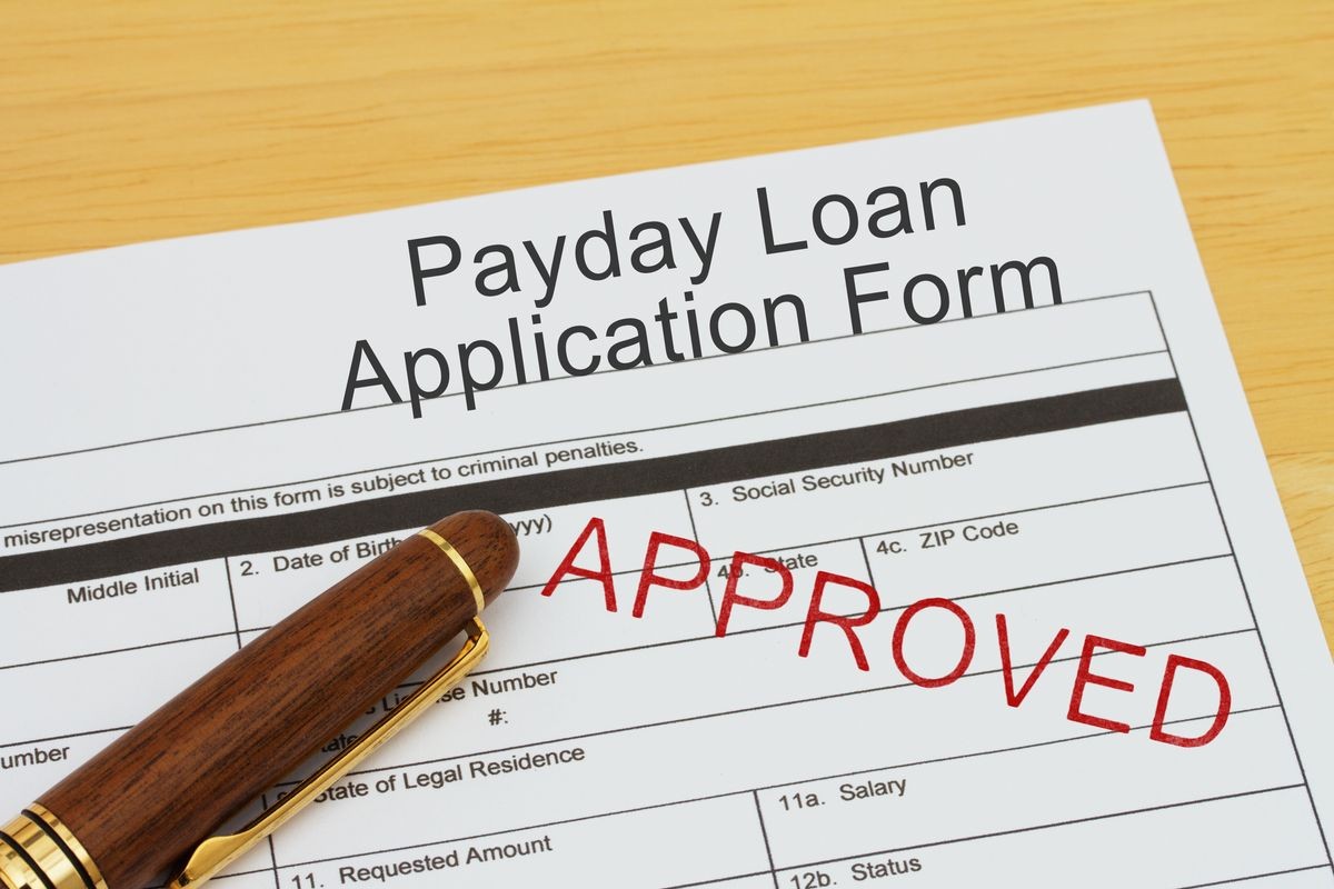 Applying for a Payday Loan Approved, Payday loan application form with a pen on a desk with an approved stamp